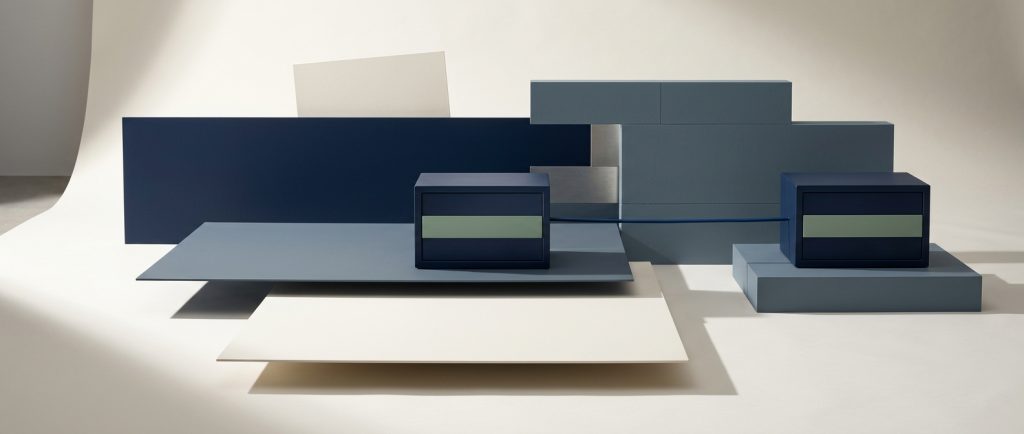 Nightly off-machine backups and security A navy strongbox with an identical second strongbox on its own separate plinth joined by a single line, behind a partial wall, representing a nightly backup kept off the machine it protects.