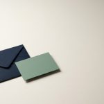 Contact Virtucom about managed services A navy envelope lying squared with a small sage card overlapping one corner, quiet and direct.