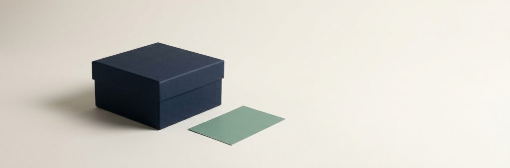 The privacy commitment and retention policy A closed navy box with its lid squarely on and a sage card lying beside it, nothing spilling out.