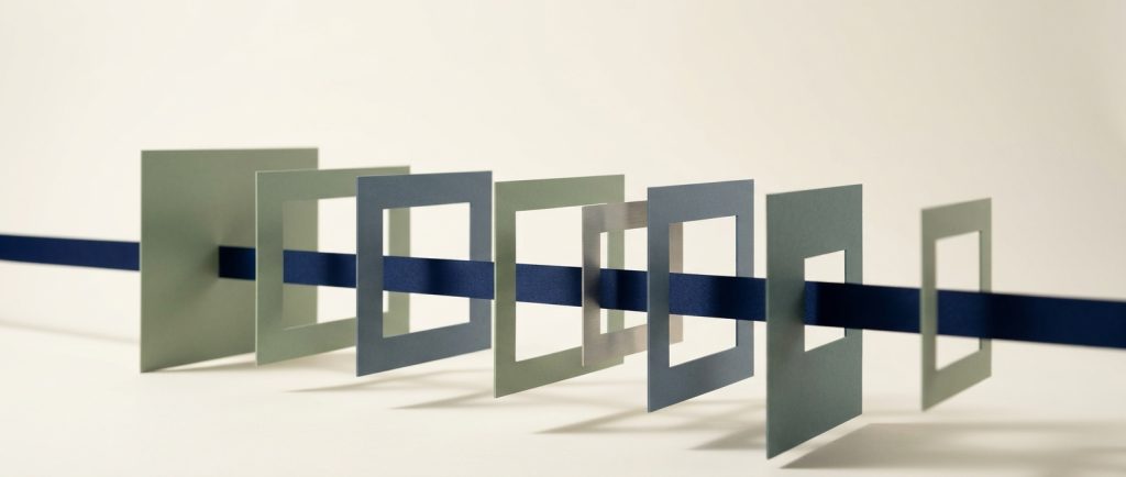 A continuous navy ribbon passing cleanly through seven upright frames of different apertures, representing one operation running through every stage without interruption.